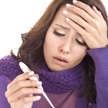 woman with the flu taking her temperature