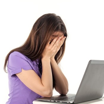 women covering her face in front of laptop