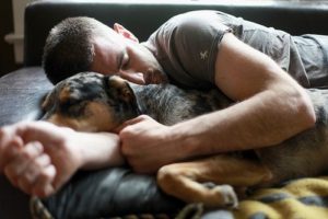 Image of man cuddling with dog