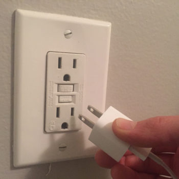 unplugging a white phone charger from the wall outlet