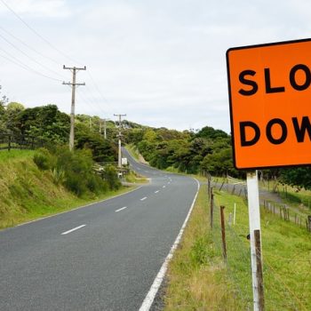 Orange road sign that reads "Slow Down"